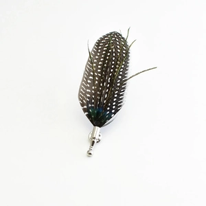 Detailed view of handmade feather brooch with black and white spots and green peacock sheen