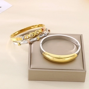Detailed view of intertwined 18K gold and silver knot bracelets on a display stand
