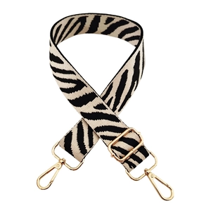 Detailed view of zebra pattern woven bag strap with adjustable gold lobster clasps