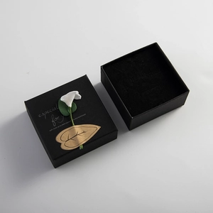 Elegante scatola regalo nera in carta kraft con fiore 3D bianco e decoro foglia dorata