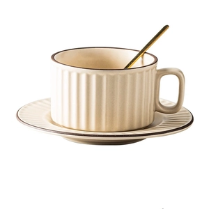 Detail of matte beige ceramic coffee cup with vertical stripe texture and golden spoon