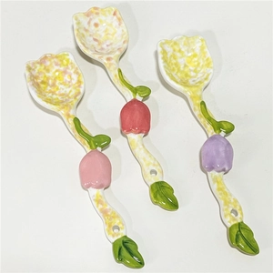 Three cute tulip-shaped ceramic dessert spoons with floral heads and green leaf handles