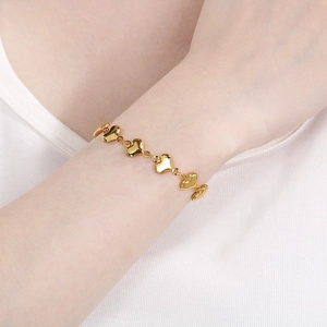 Macro detail of gold-plated hollow heart link bracelet worn on a woman's wrist