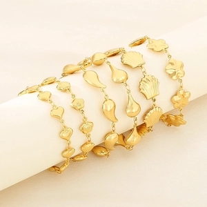 Detailed close-up of gold-plated heart and shell pendants on a stainless steel bracelet