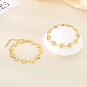 Detail of golden stainless steel bracelets with heart and flower charms and Fu character