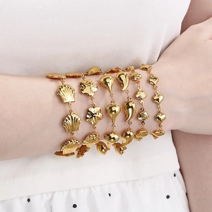 Gold stainless steel bracelet set with shell, flower, drop and heart charms on model wrist