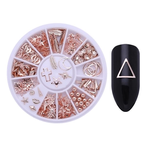Macro view of rose gold nail art charms set in a white wheel case with shell and star shapes