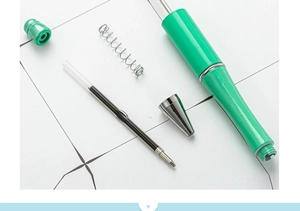 Disassembled view showing green DIY beadable pen parts, ink refill and metal spring