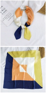 Detail of a geometric color block satin scarf with navy, yellow, and orange patterns