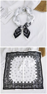 Detailed flat lay of a black and white paisley silk scarf with elegant wide border