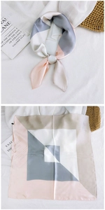 Detail view of geometric silk scarf showing folded knot and flat layout on soft fabric