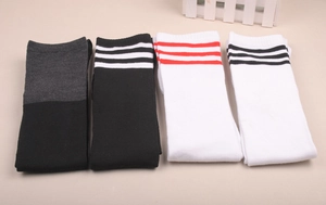 Flat lay of knit over-the-knee socks featuring classic three-stripe athletic patterns