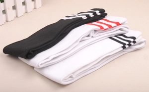 Detailed view of striped knee-high socks in black and white stacked on flat surface