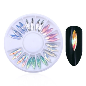 Detail of aurora teardrop nail charms in a round divider box with display on black nails