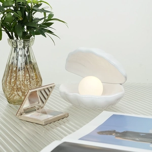Minimalist white shell night light with glowing pearl on a nightstand for home decor