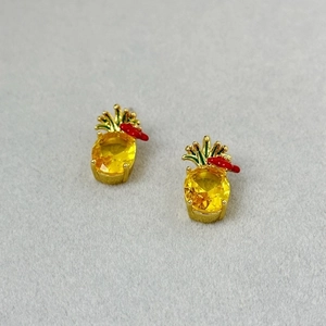 Close-up of yellow pineapple stud earrings with faceted crystals and green leaf accents