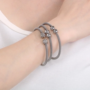 Detail showing set of three silver mesh textured open bangles worn by model