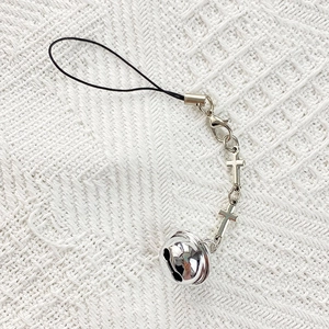 Close-up of Y2K silver metallic cross charms and bell pendant on white knit background