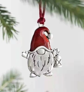 Detail of a red gnome Christmas ornament with a lantern on a green pine branch