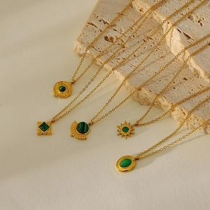 Vintage gold necklaces with green turquoise and malachite pendants on stone background