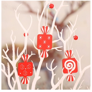 Close-up of three red wooden candy ornaments with white patterns for Christmas tree