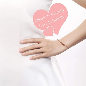 Close-up of infinity symbol bracelet in rose gold on model with luxury ruby accents