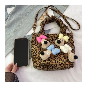 Close-up of leopard print handbag with colorful bow-tie cartoon dog plush pendants