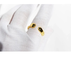 Macro close-up of a minimalist gold irregular wave ring on a gloved finger detail