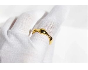 Macro shot of minimalist gold irregular wavy ring with smooth polished metallic finish