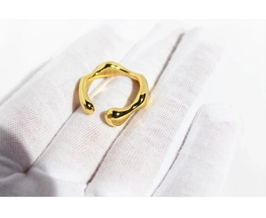 Close-up of a glossy gold adjustable ring featuring a unique irregular wave texture design