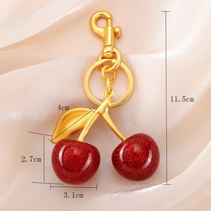 Sparkly red cherry keychain with gold metal leaves and lobster clasp on silk fabric