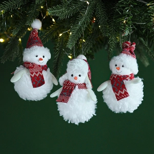 Three plush snowman ornaments with red scarves hanging on a festive Christmas tree branch
