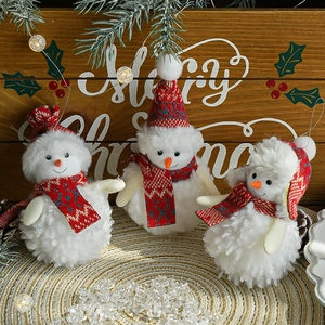 Three plush snowman ornaments with red scarves and hats on a festive wooden surface