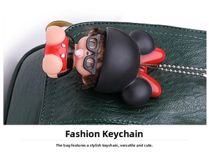 Close-up of a cute doll bag charm with glasses on dark green lychee grain leather handbag