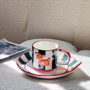 Detail of hand-painted ceramic coffee cup featuring red trim and 3D orange dog handle