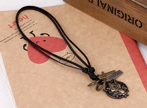 Macro detail of vintage black leather necklace with bronze wolf head and engraved charms
