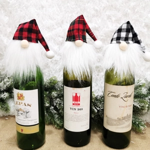 Three Nordic Christmas gnome wine bottle covers in festive red and green plaid patterns