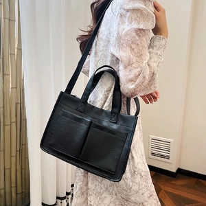Minimalist black tote bag in PU leather featuring front pockets and large capacity design