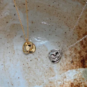 Detailed view of gold and silver irregular organic pendants on fine cross chains in a bowl