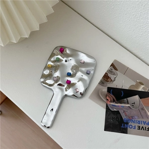 Square silver handheld makeup mirror with wavy texture and colorful rhinestones