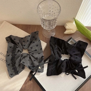 Detailed close-up of grey and black lace hair scrunchies with elegant ribbon bow charms