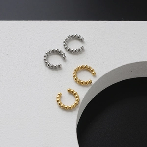 Detailed view of beaded C-shaped ear cuffs in gold and silver finish on white background
