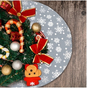 Detail of grey Christmas tree skirt with white snowflake patterns on wooden floor