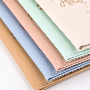 Close-up of stacked PU leather passport covers in pastel colors with white stitching