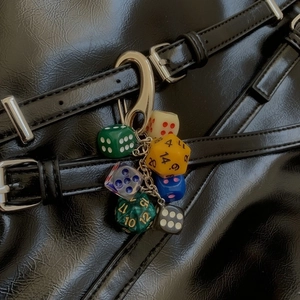 Multicolor resin dice keychain accessory with silver metal clasp on black leather bag
