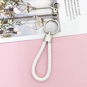Close-up of white braided leather keychain with polished silver metal ring and clasp