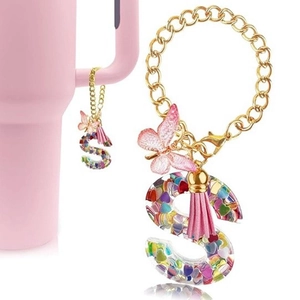 Close-up of letter S resin keychain with colorful sequins and pink tassel on a cup handle