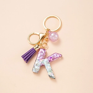 Resin letter K keychain with purple glitter, silk tassel and gold alloy clasp on light beige