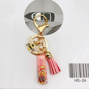 Detail of bee metal keychain with pink tassel and glitter resin letter pendant charm