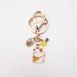Close-up of Maneki Neko keychain with lucky gold coin and rainbow star pendant